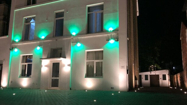 Ein Gebäude mit mehreren Fenstern und Türen, beleuchtet durch grüne und weiße Lichter.
