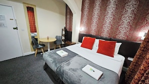 Ein Hotelzimmer mit einem Bett, einem kleinen Tisch mit Stühlen, einem Schreibtisch und einer Wand mit Muster.