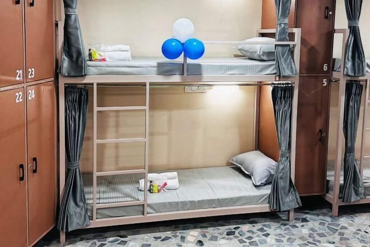 A bunk bed room with a wardrobe, a small table, and a curtain.