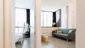 Une chambre d’hôtel moderne comprenant un lit, un coin salon avec un canapé, une petite table et une fenêtre avec des rideaux.