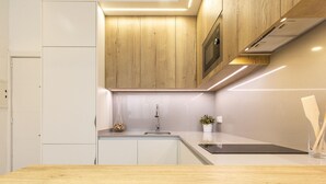 Une cuisine moderne avec des meubles en bois, un évier en acier inoxydable et un four à micro-ondes encastré.