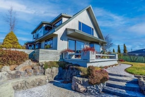 A modern two-story house with a stone pathway leading to the entrance, surrounded by a well-maintained garden. - The Lake House (Lake Tekapo)
