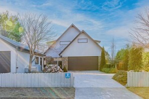 Ein zweigeschossiges Haus mit Garage, Vorgarten und weißem Zaun.