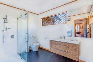 A modern bathroom with a glass shower enclosure, a wooden vanity, and a large mirror. - The Lake House (Lake Tekapo)