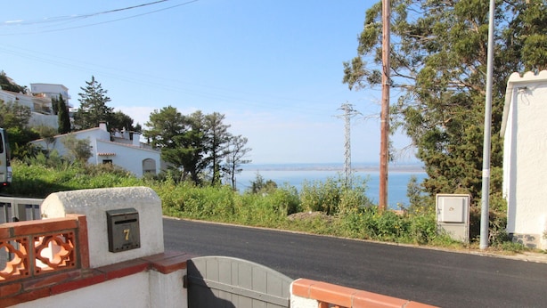 A coastal road with a gate, a mailbox, and a utility box. - Getaway in Roses: Comfort, Terrace & Shared Pool (Roses)