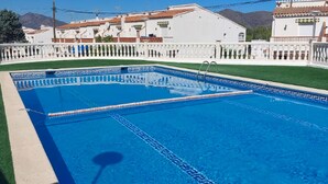 A swimming pool with lane dividers, surrounded by a white fence and a grassy area. - Getaway in Roses: Comfort, Terrace & Shared Pool (Roses)