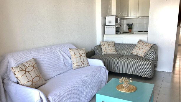 A living room with a light-colored sofa, a striped sofa, and a turquoise coffee table.