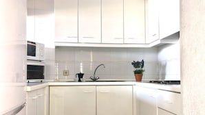 A kitchen with white cabinets, a built-in microwave, a sink, and a potted plant.