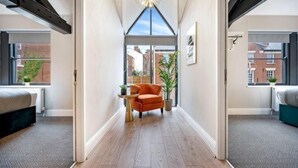 A narrow hallway with a ceiling light fixture, a chair, and a small table. - Host & Stay The Coachouse at Pilgrim St (Liverpool)