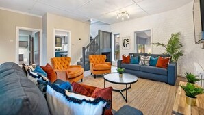 A modern living room with a sofa, armchairs, a coffee table, and a fireplace. - Host & Stay The Coachouse at Pilgrim St (Liverpool)