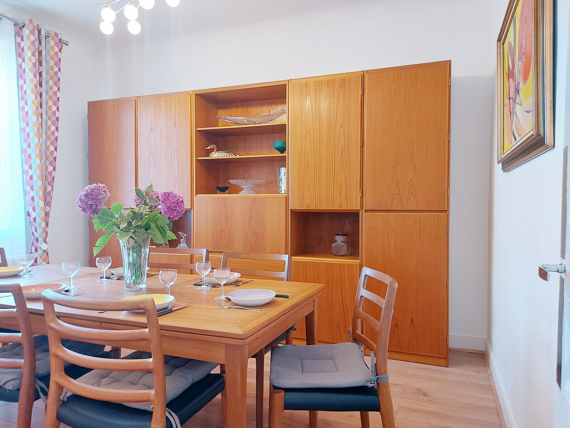 Un coin repas comprenant une table en bois, des chaises et un meuble avec des étagères.