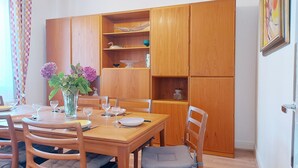 A dining area with a wooden table, chairs, and a cabinet with shelves. - Cozy lodging near Chartres - 6 guests (Mainvilliers)
