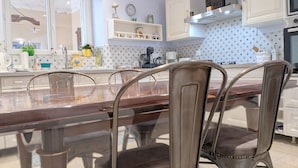 A modern kitchen with a wooden dining table, metal chairs, white cabinets, and a tiled backsplash. - Spacious house with covered terrace and parking in natural area (Méobecq)