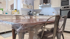 A modern kitchen with white cabinets, a wooden dining table, and stainless steel chairs. - Spacious house with covered terrace and parking in natural area (Méobecq)