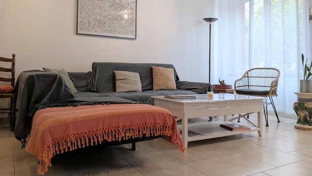 A cozy living room with a sofa, a coffee table, and a chair. There is a framed artwork on the wall and a floor lamp. - Spacious house with covered terrace and parking in natural area (Méobecq)