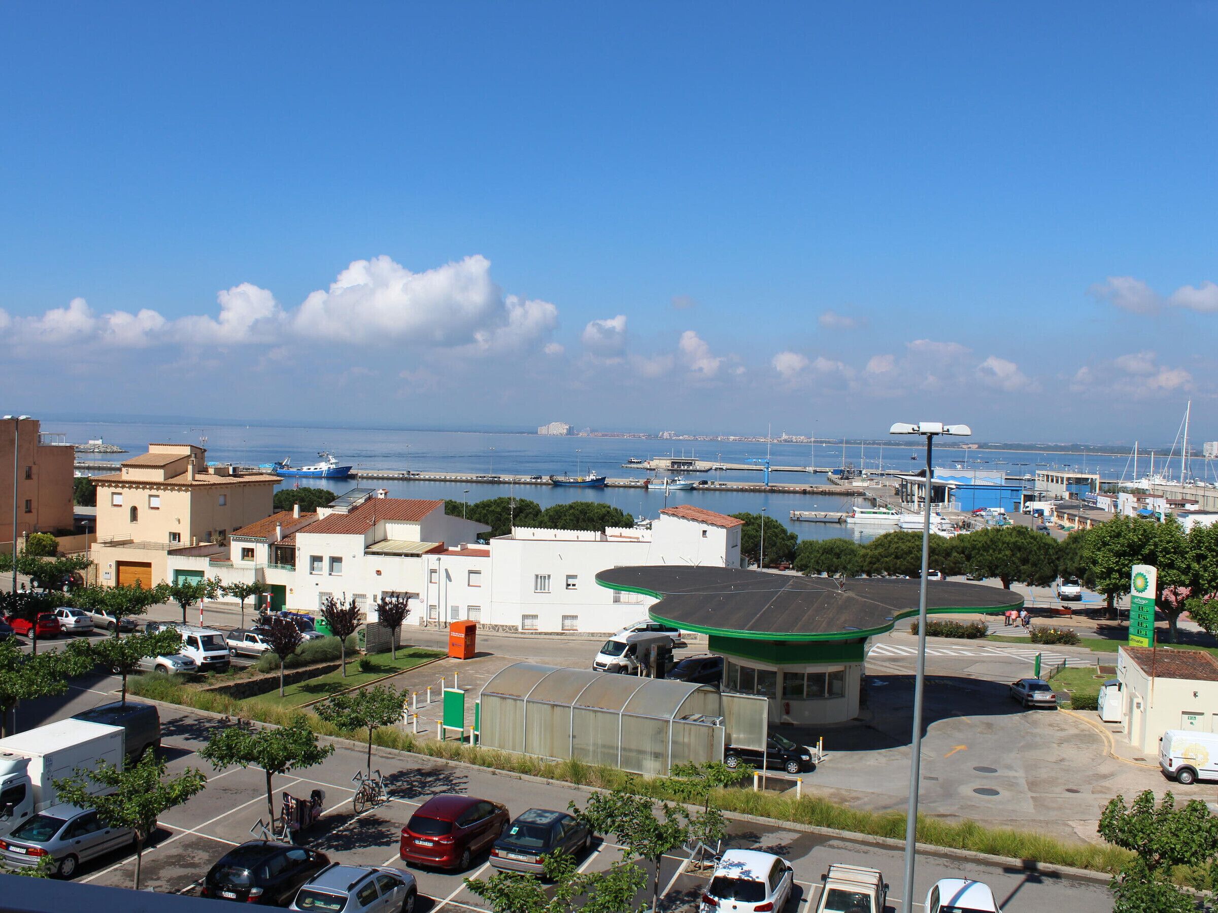 A coastal town with a marina, buildings, and parked cars.