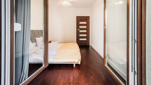Quarto com cama, ventilador de teto e porta que dá para outro cômodo.