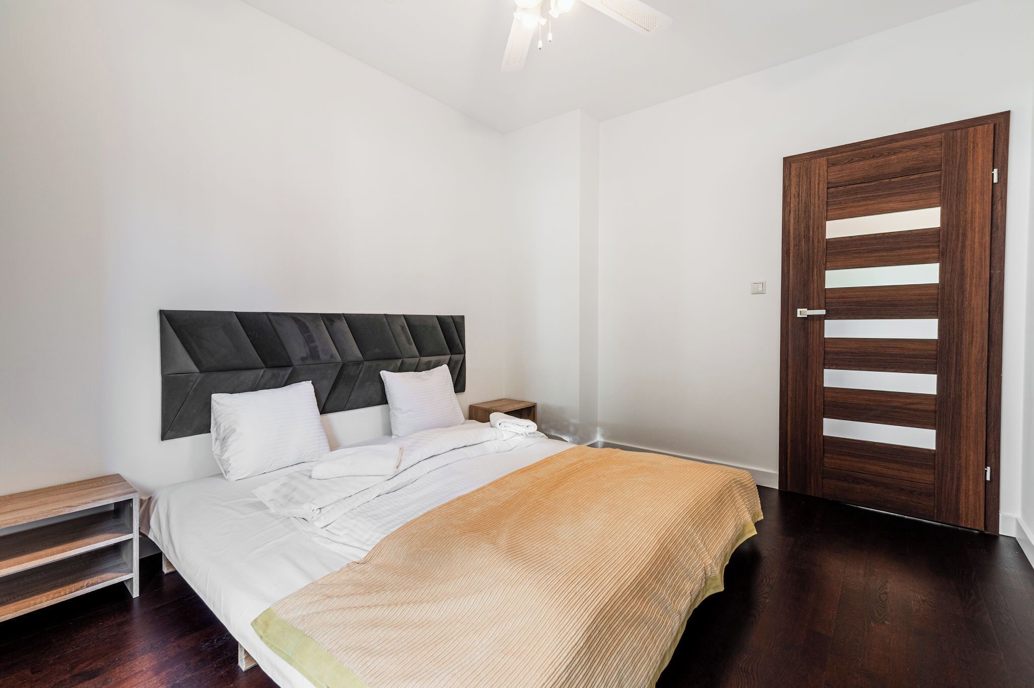 Un dormitorio con cama, mesita de noche y puerta de madera.