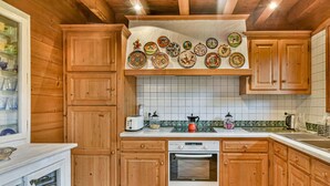 Une cuisine avec des meubles de rangement en bois, un pare-feu en carrelage, un grille-pain, une bouilloire et un lave-vaisselle.
