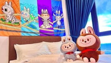 A bed with pillows and a wall tapestry with cartoon characters.