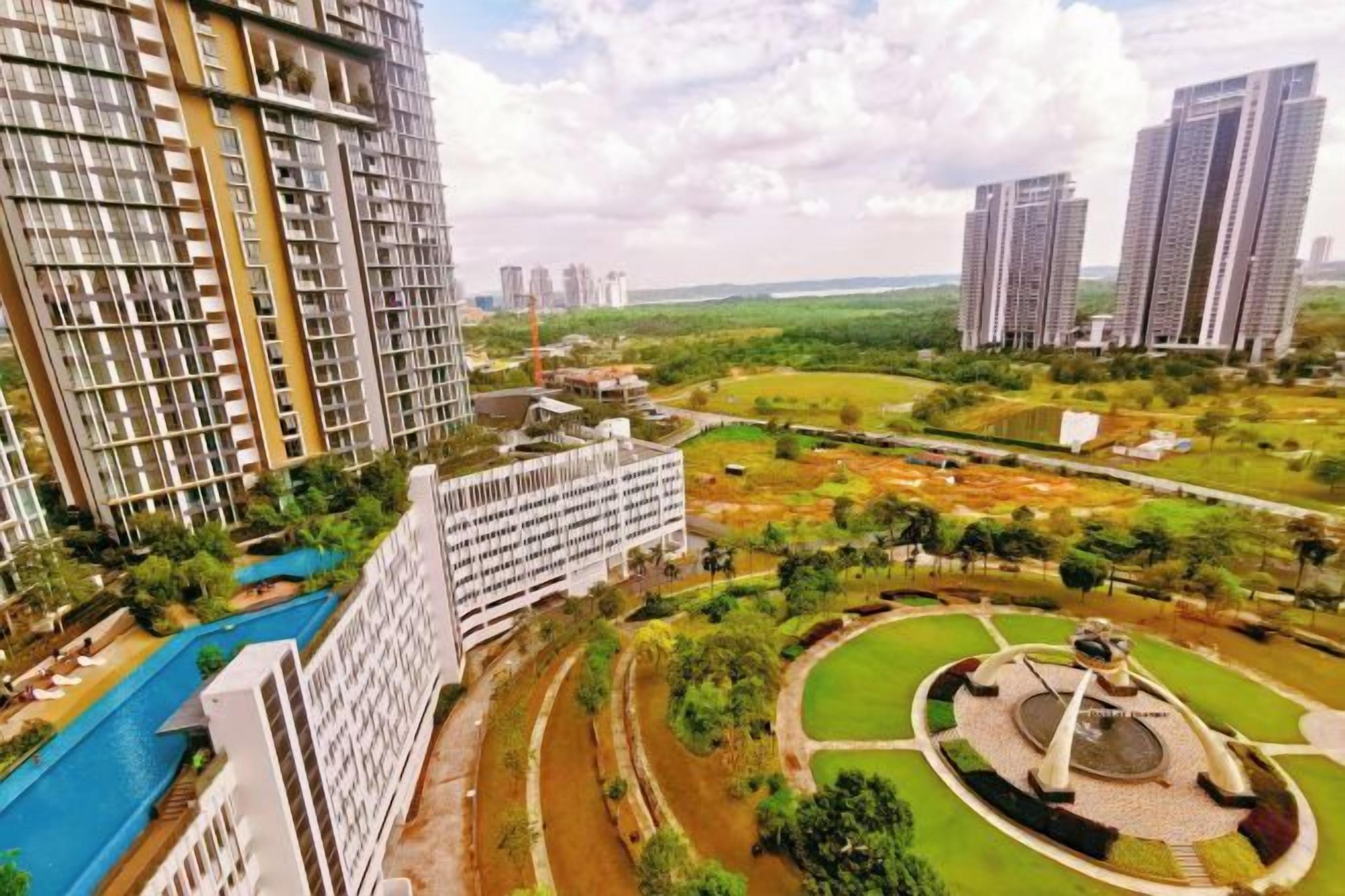 A high-rise residential building with a swimming pool, a landscaped park, and a circular monument.