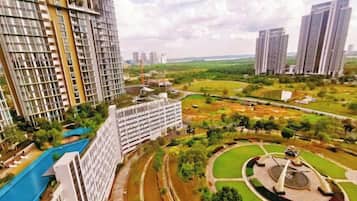 A high-rise residential building with a swimming pool, a landscaped park, and a circular monument.