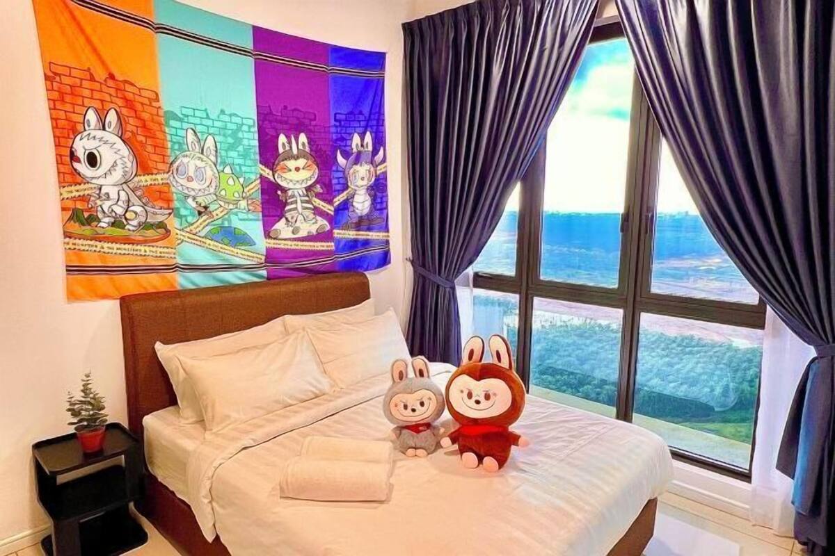 A bed with a view of a landscape, a wall with colorful artwork, and two plush toys on the bed.