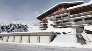 A multi-story building with balconies, surrounded by snow-covered trees and a clear sky. - Comfortable 2-room apartment for 5 with private parking (Le Grand-Bornand)