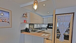A modern kitchen with a central island, a coffee machine, and a framed picture on the wall. - Comfortable 2-room apartment for 5 with private parking (Le Grand-Bornand)