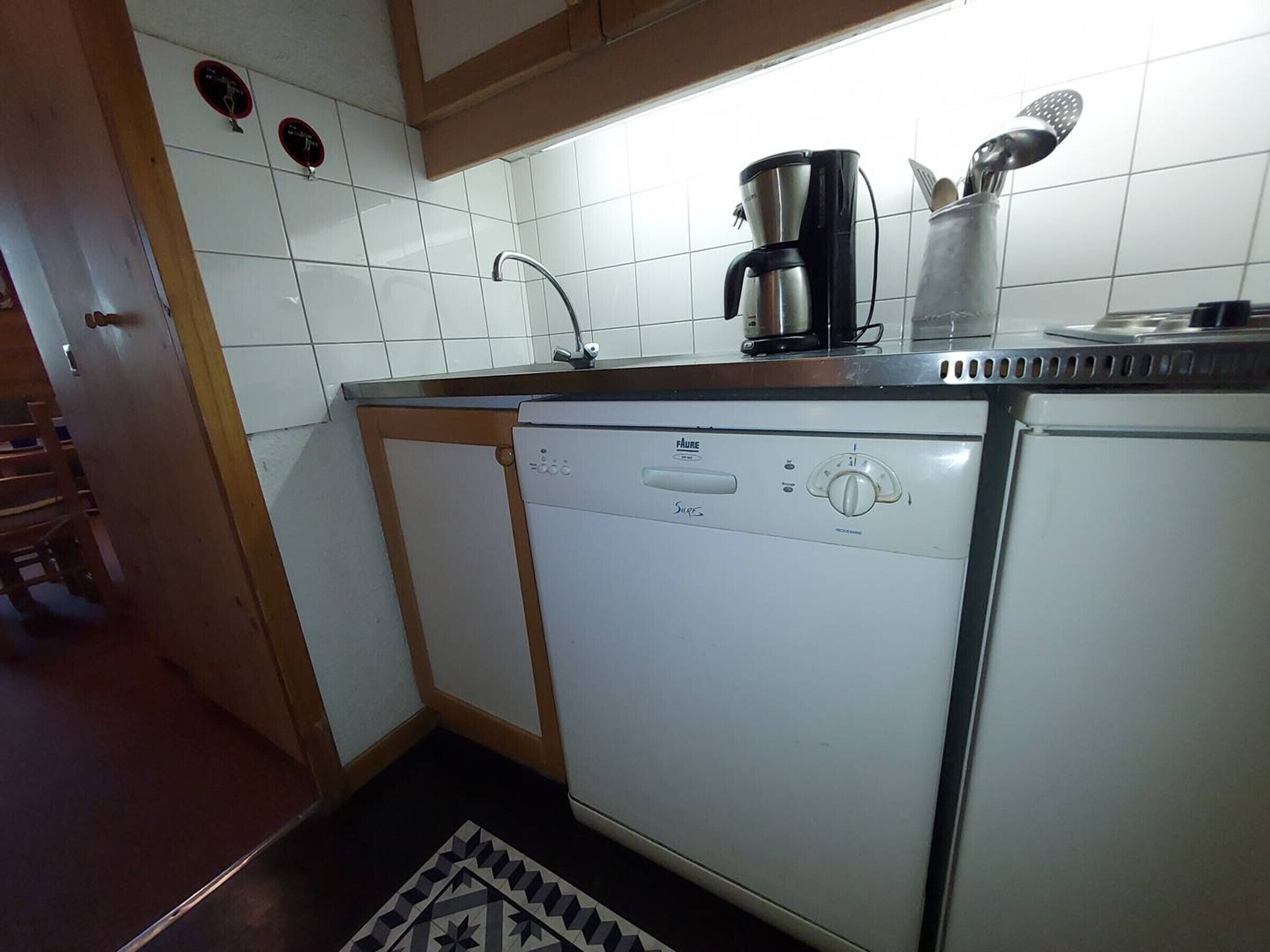 Une cuisine compacte équipée d’un lave-vaisselle, d’une machine à café et d’un évier.