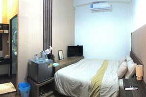A hotel room with a bed, a desk with a computer, a TV, and an air conditioning unit. - nine guesthouse (Chiang Rai)
