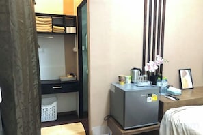 A compact hotel room with a bunk bed, a small kitchenette, a desk with a refrigerator, and a bedside table with a vase of flowers. - nine guesthouse (Chiang Rai)