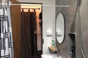 A bathroom with a shower, a toilet, a sink, a mirror, and a towel rack. - nine guesthouse (Chiang Rai)