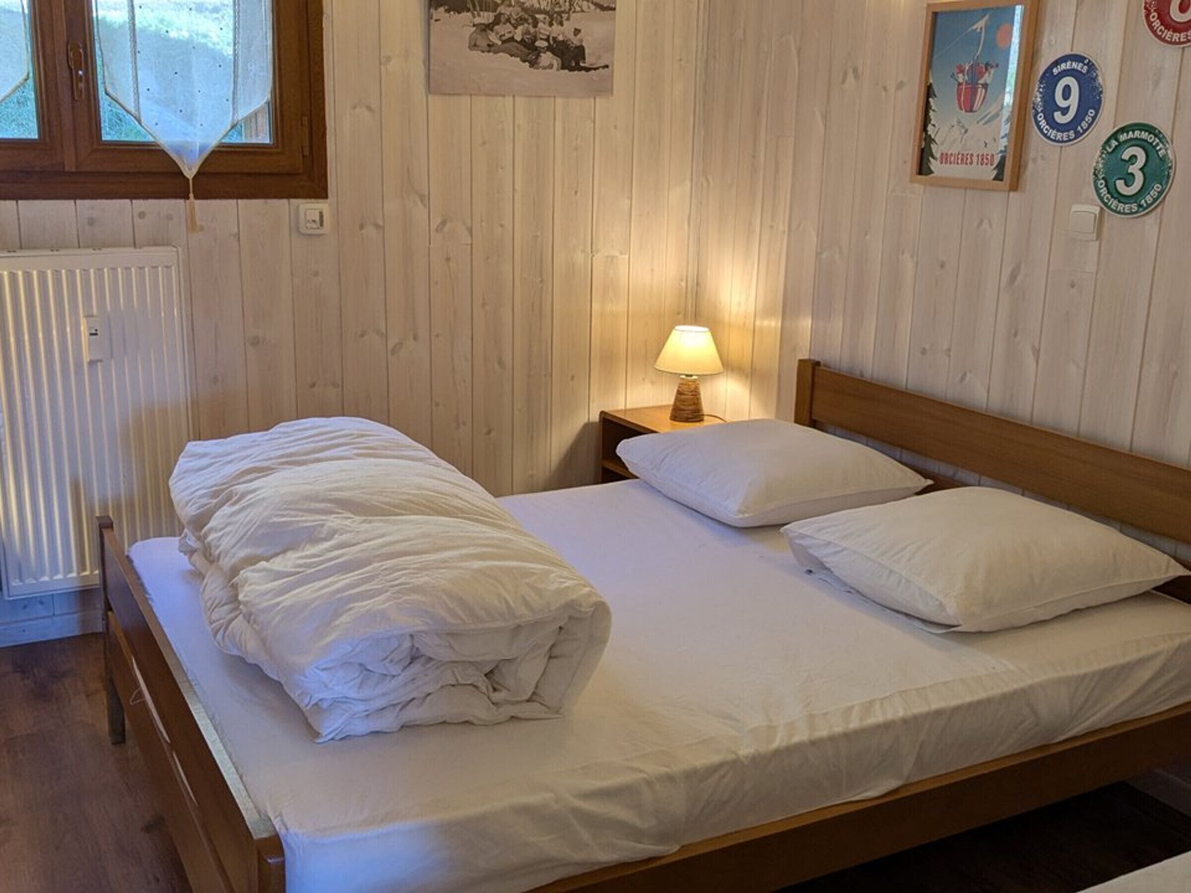 Una cama bien hecha con sábanas blancas en una habitación con paneles de madera.