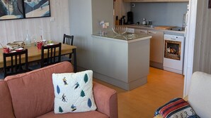 A compact living space with a kitchenette, a dining area, and a sofa with a ski-themed pillow.