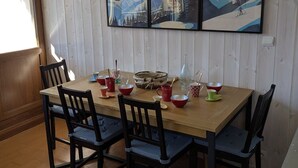 A dining table with chairs, a vase, and a framed picture of a mountain scene.
