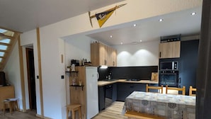 Una cocina compacta con electrodomésticos modernos, armarios de madera y una zona de comedor con mantel estampado.