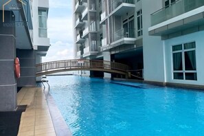 A swimming pool with a bridge, a lifebuoy, and a building with balconies. - Apartment @ KSL D'Esplanade JB - 4R3B (Johor Bahru)