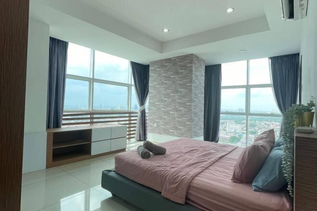 Une chambre moderne avec un grand lit, un téléviseur intégré et une vue sur la ville.