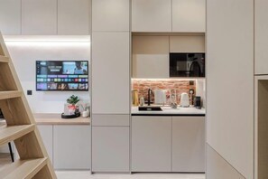 A modern kitchen with a built-in TV, a brick backsplash, and a minimalist design.