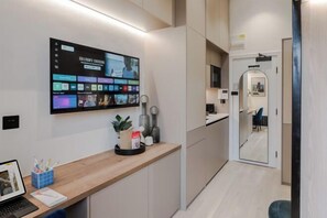 A modern kitchen with a large digital screen displaying various content, a wooden countertop, and a mirror reflecting the room. - Kensington The Loft XL (London)