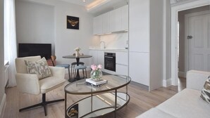 A modern living room with a sofa, coffee table, and a small dining table. - B Comfort Apartments (London)
