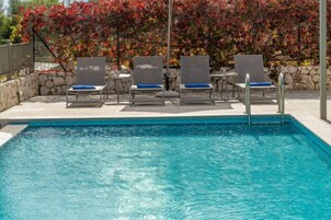 Una piscina con sillas de descanso y una pared de piedra.