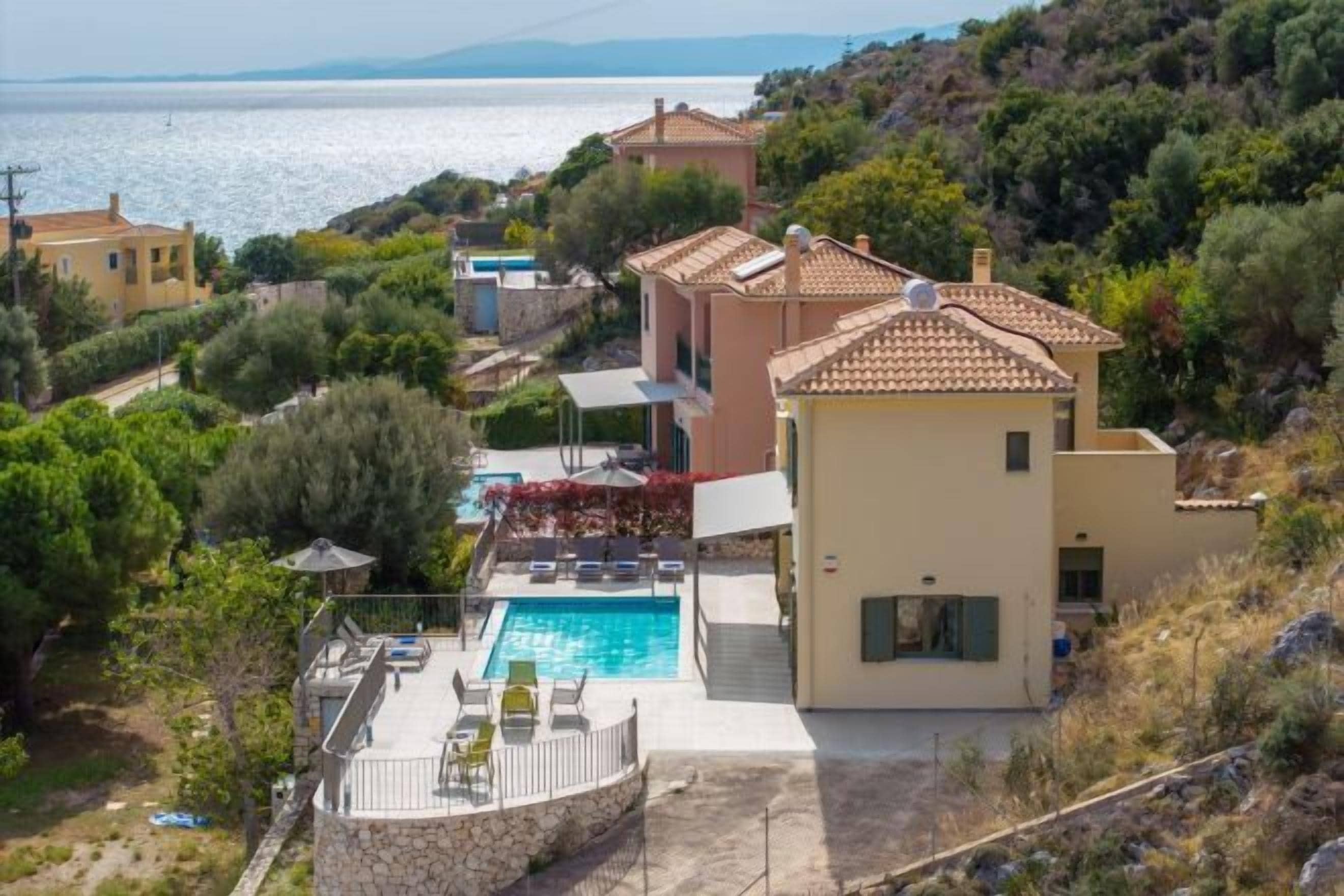Uma villa em estilo mediterrâneo com piscina, jardim em terraços e vista para o mar.