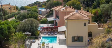 En villa i medelhavsstil med en swimmingpool, en terrasserad trädgård och utsikt över havet.