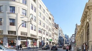 En byggnad med flera våningar, en böjd fasad, stora fönster och en klar himmel.