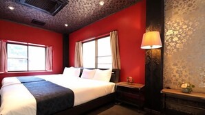 A hotel room with a large bed, two windows with curtains, a nightstand, a lamp, and a decorative wall. - Shirahama no Kaze (Shirahama)
