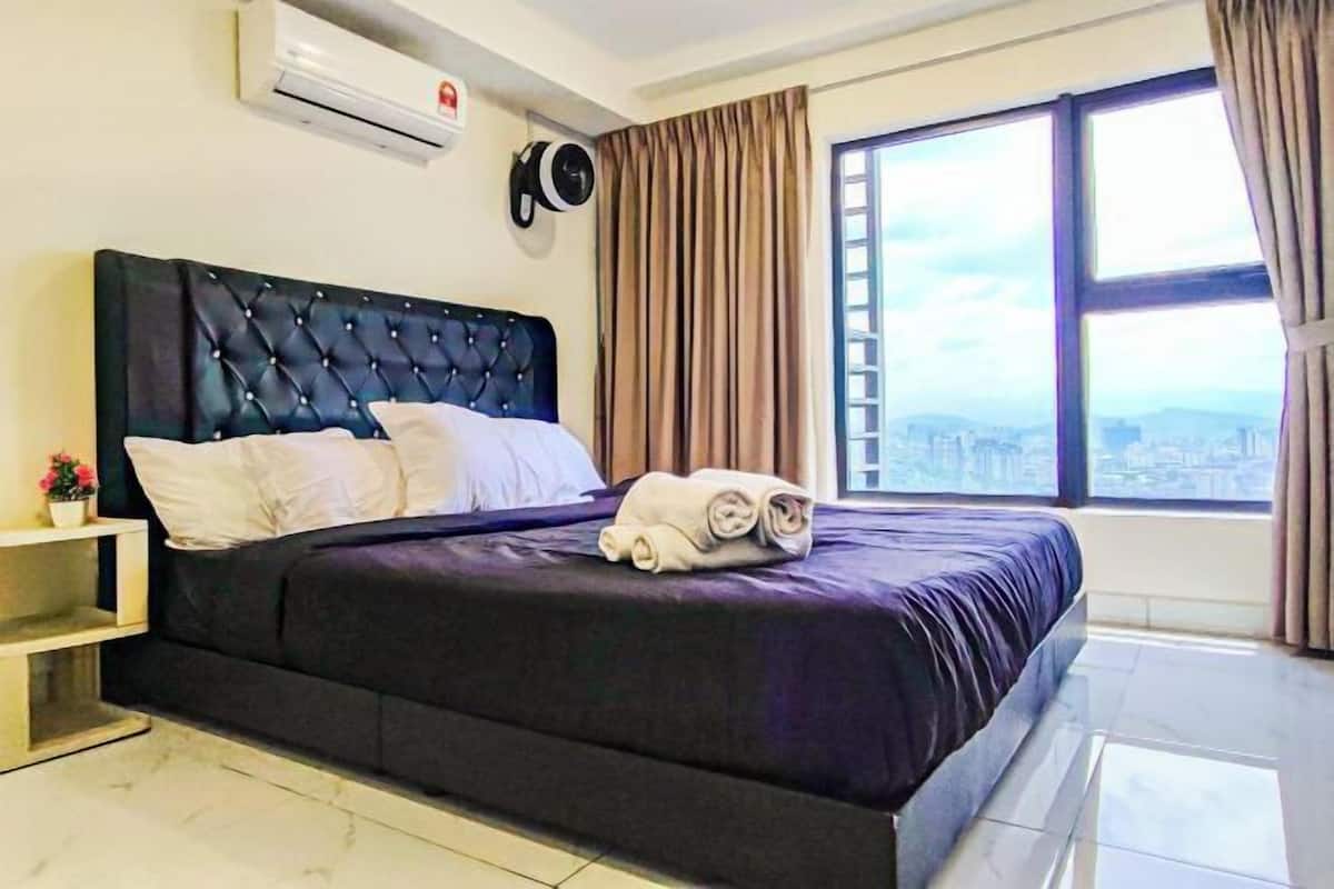 Hotelkamer met een groot bed, nachtkastje, airconditioning, raam met gordijnen en uitzicht op de stad.