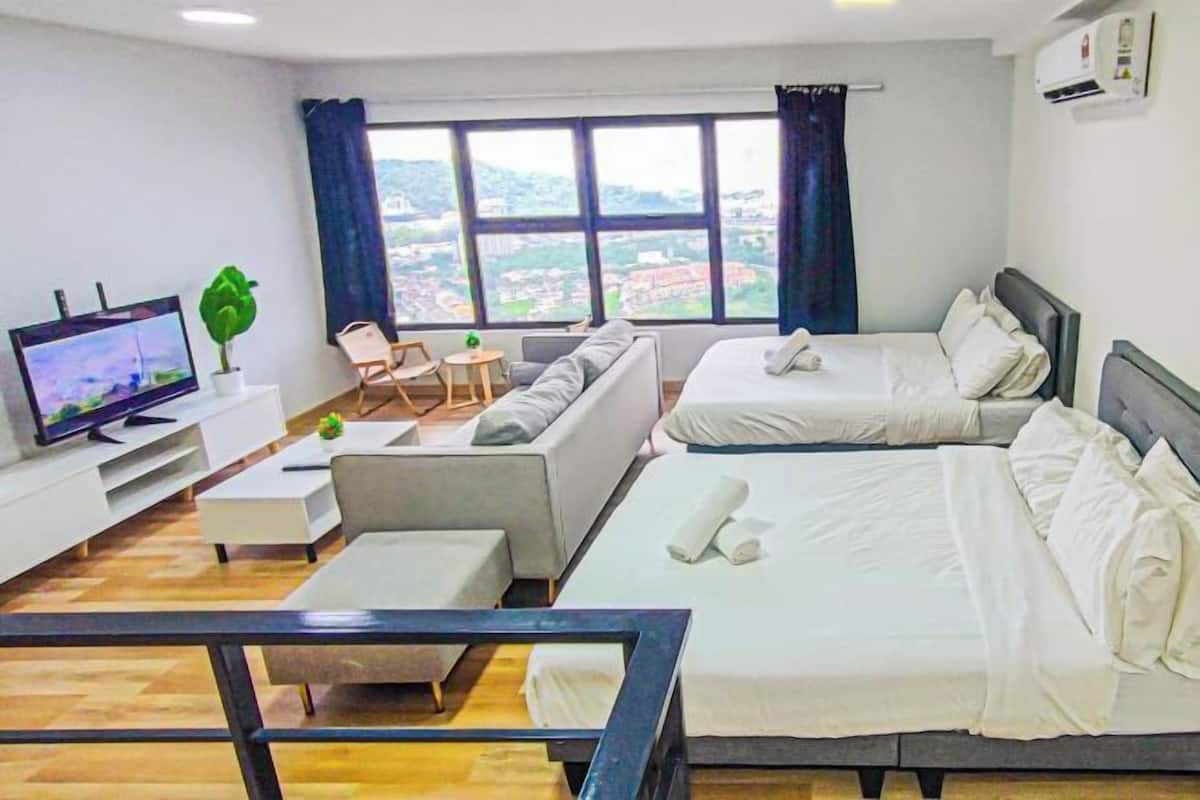 Een hotelkamer met twee bedden, een televisie, een bank, een kleine tafel en uitzicht op de stad.