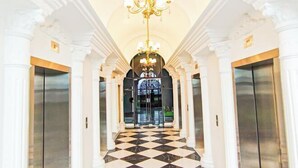 Un vaste hall d’entrée avec un sol à carreaux, des colonnes blanches et un lustre.
